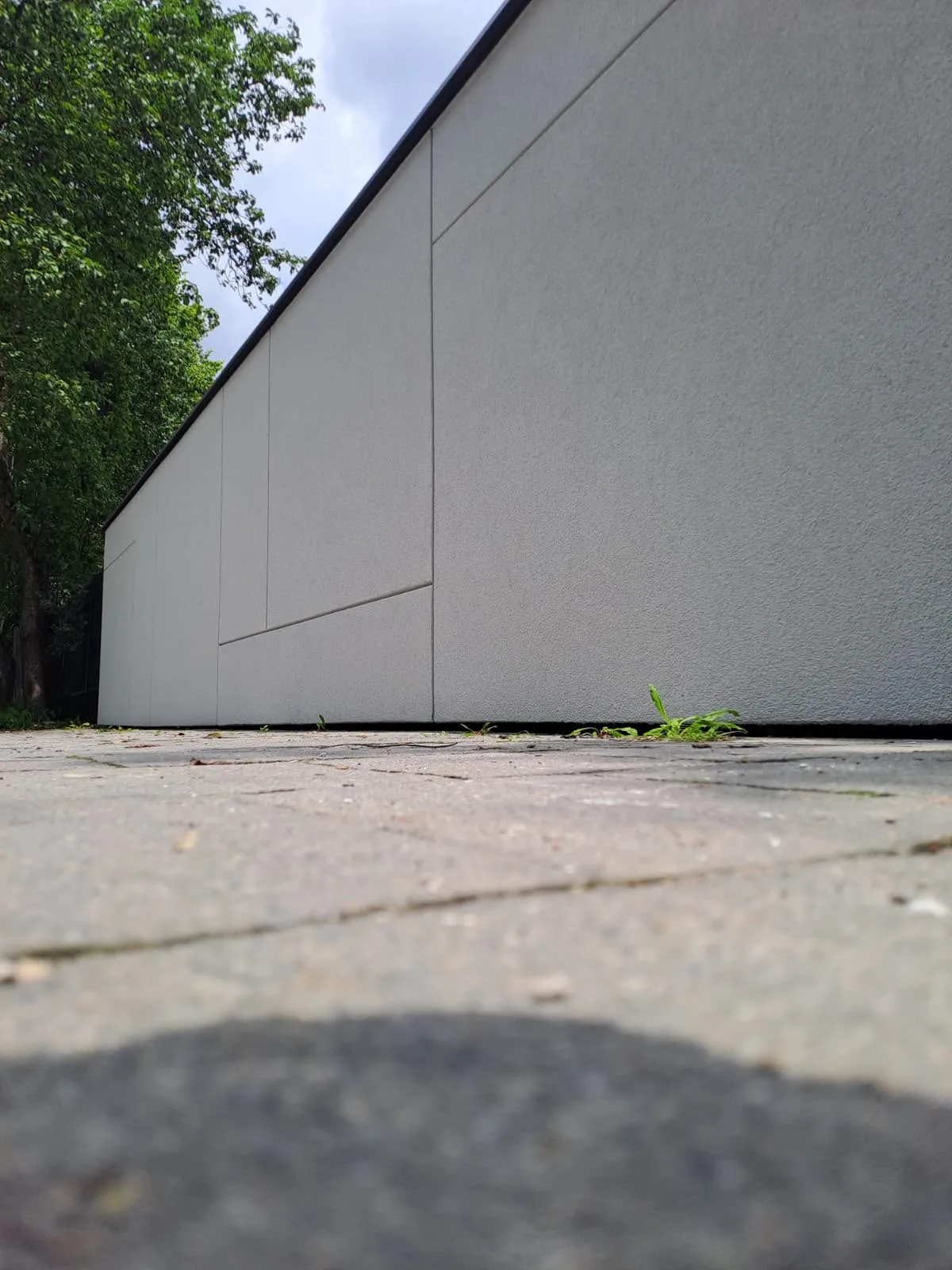 Elewacja budynku z tynkiem elewacyjnym w jasnym kolorze, widoczna z niskiej perspektywy