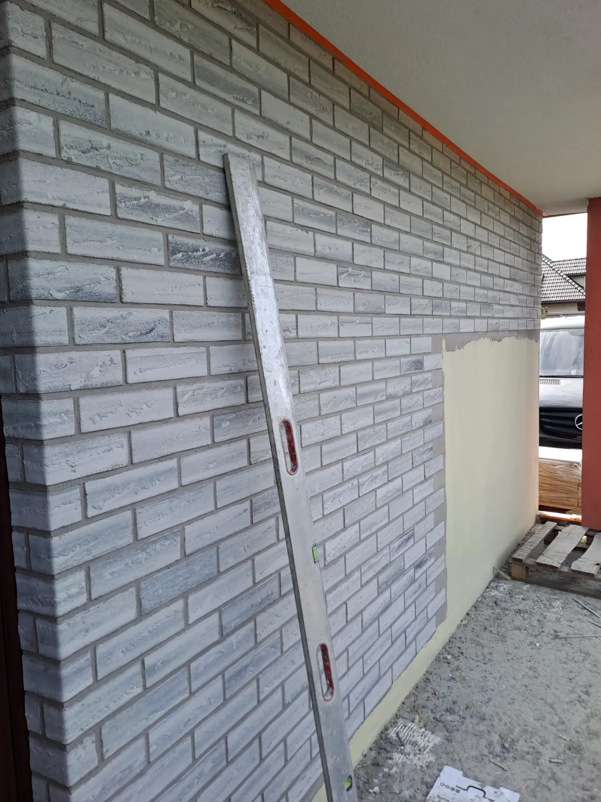 Fragment elewacji z tynkiem architektonicznym imitującym klinkier. Widoczny poziomica